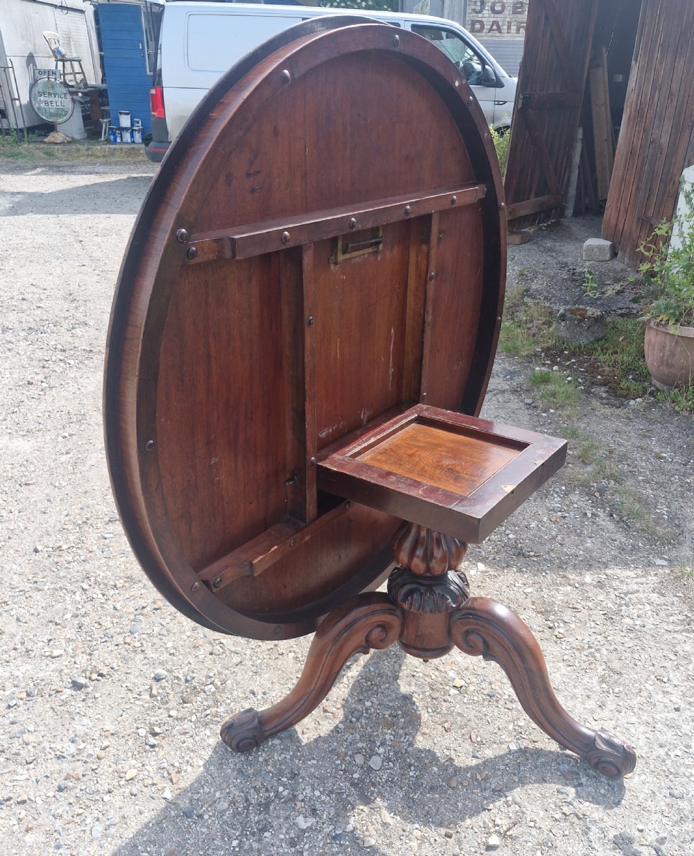 A mid-19th-century circular rosewood centre table shown tilted vertically to display its symmetrical figured grain and carved pedestal base. View VII