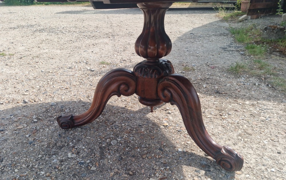 A mid-19th-century circular rosewood centre table shown tilted vertically to display its symmetrical figured grain and carved pedestal base. View XI