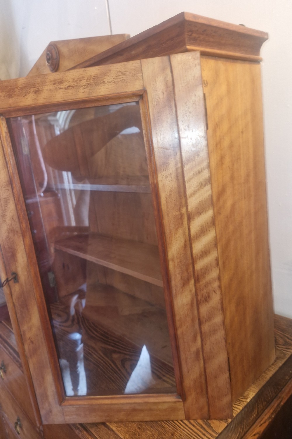 A Mid-Victorian satinbirch wall cabinet featuring two glazed doors, internal wooden shelves, and a pediment top with a central turned round patera. View IV