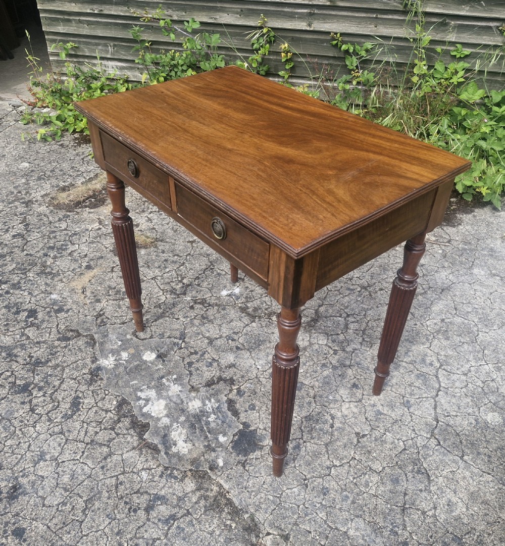 A rectangular Edwardian mahogany side table featuring two drawers with brass handles and fluted turned legs.