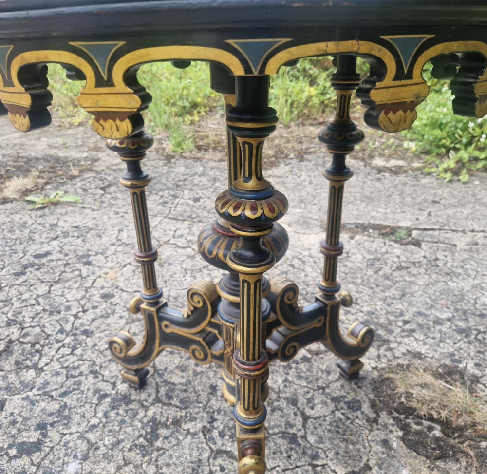A nineteenth-century circular occasional table featuring a blue fabric inlay top surrounded by polychrome and gilt painting on an ebonised carved pedestal base. View XI