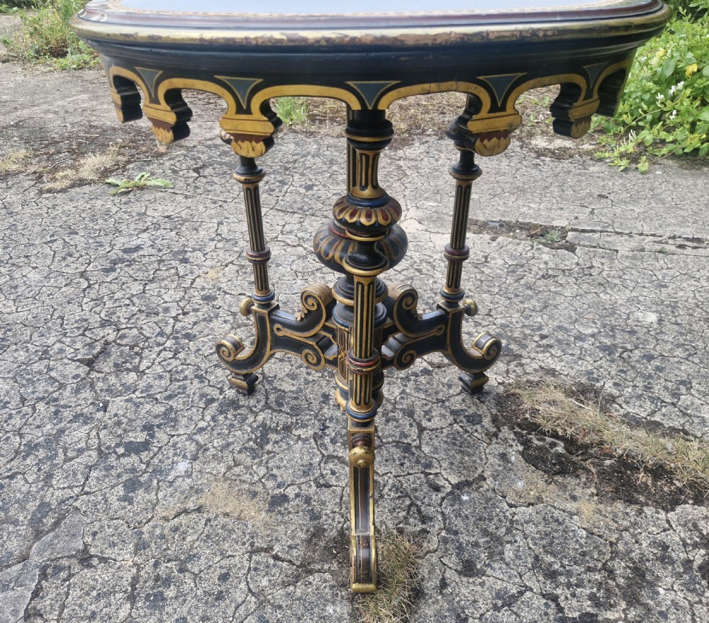 A nineteenth-century circular occasional table featuring a blue fabric inlay top surrounded by polychrome and gilt painting on an ebonised carved pedestal base. View XII