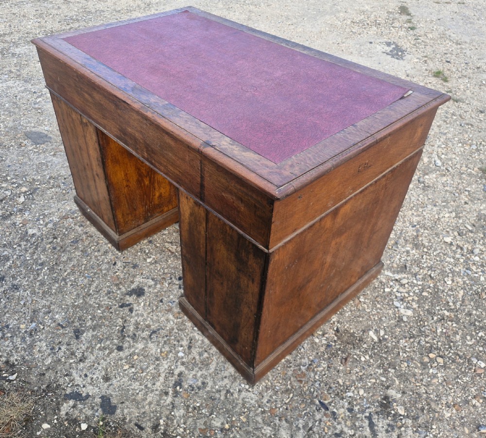 A late Victorian oak kneehole pedestal writing desk featuring a red leather writing surface, multiple drawers, and recessed flush brass handles. View II