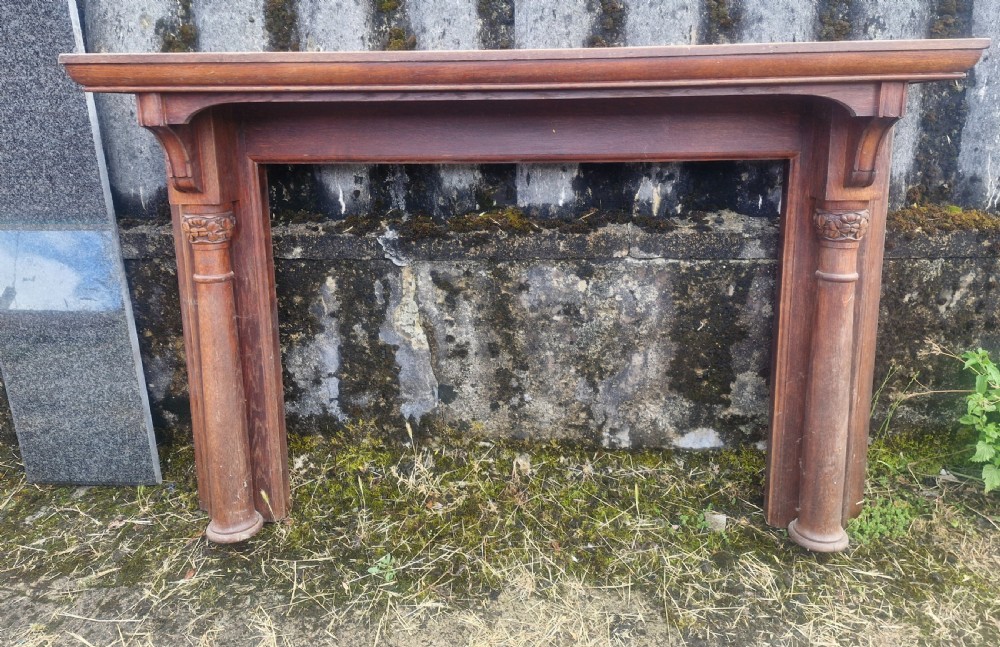 An Edwardian carved oak fire surround featuring twin column supports alongside a long polished dark granite hearth slab. View VII