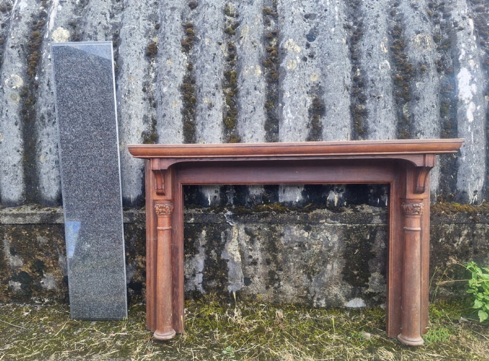 An Edwardian carved oak fire surround featuring twin column supports alongside a long polished dark granite hearth slab. View VIII