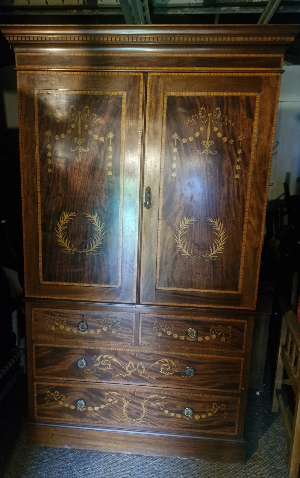 An Edwardian mahogany linen press featuring satinwood marquetry swags and laurel wreaths on the double doors above four drawers. View X