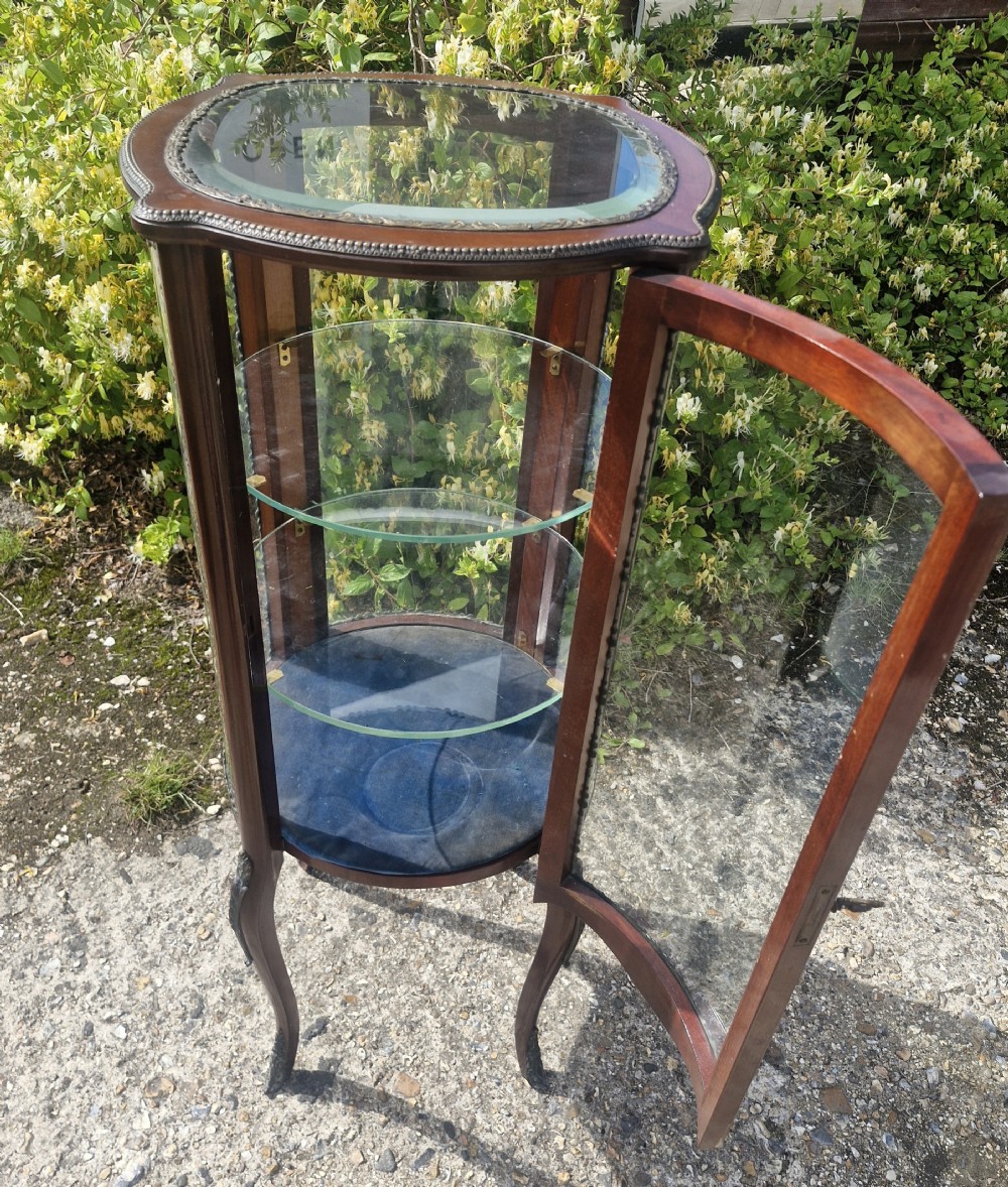 An Edwardian mahogany bijouterie display cabinet with glazed panels, internal glass shelves, gilt metal mounts, and slender cabriole legs. View X