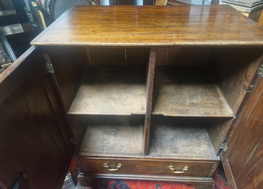 A late Georgian mahogany cupboard with two panelled doors positioned over a single wide drawer with twin brass handles, resting on bracket feet. View III