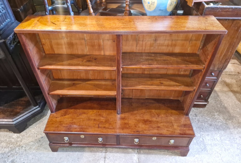 A Regency mahogany dwarf bookcase featuring open adjustable shelves above two lower drawers with brass ring handles.