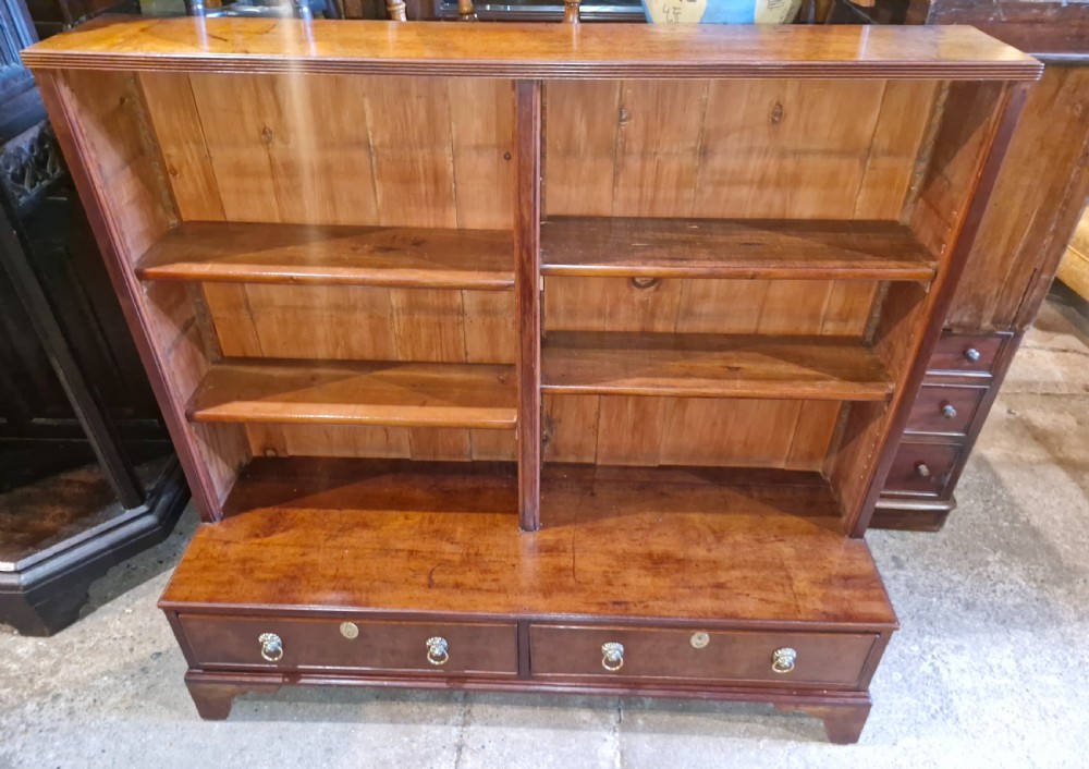 A Regency mahogany dwarf bookcase featuring open adjustable shelves above two lower drawers with brass ring handles. View V