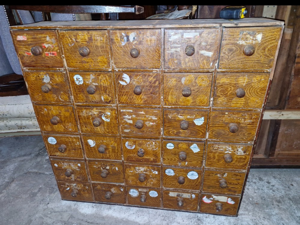 A late Victorian wooden bank of drawers featuring thirty individual drawers arranged in a five by six grid with turned wooden knob handles.
