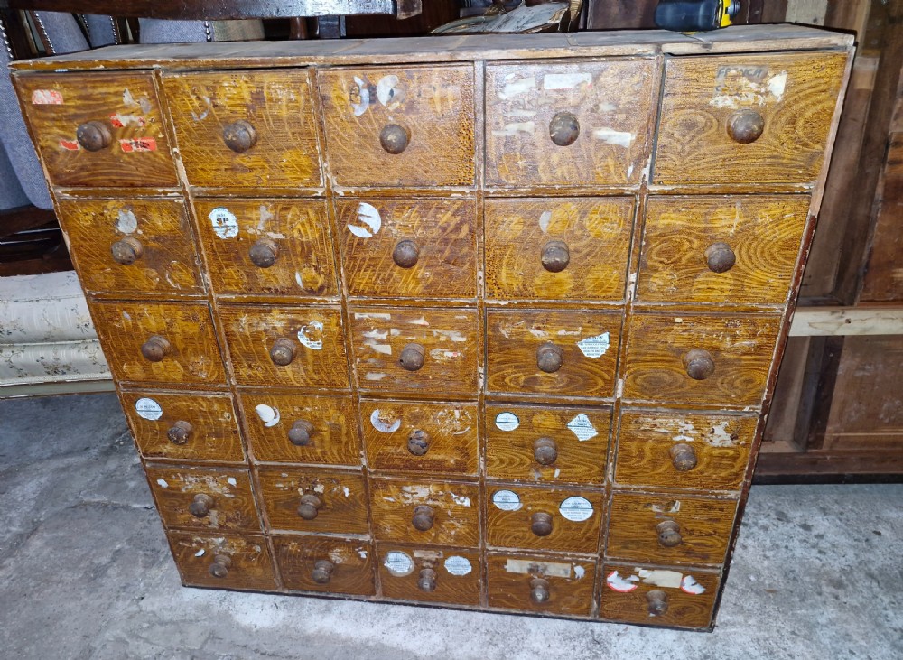 A late Victorian wooden bank of drawers featuring thirty individual drawers arranged in a five by six grid with turned wooden knob handles. View VII