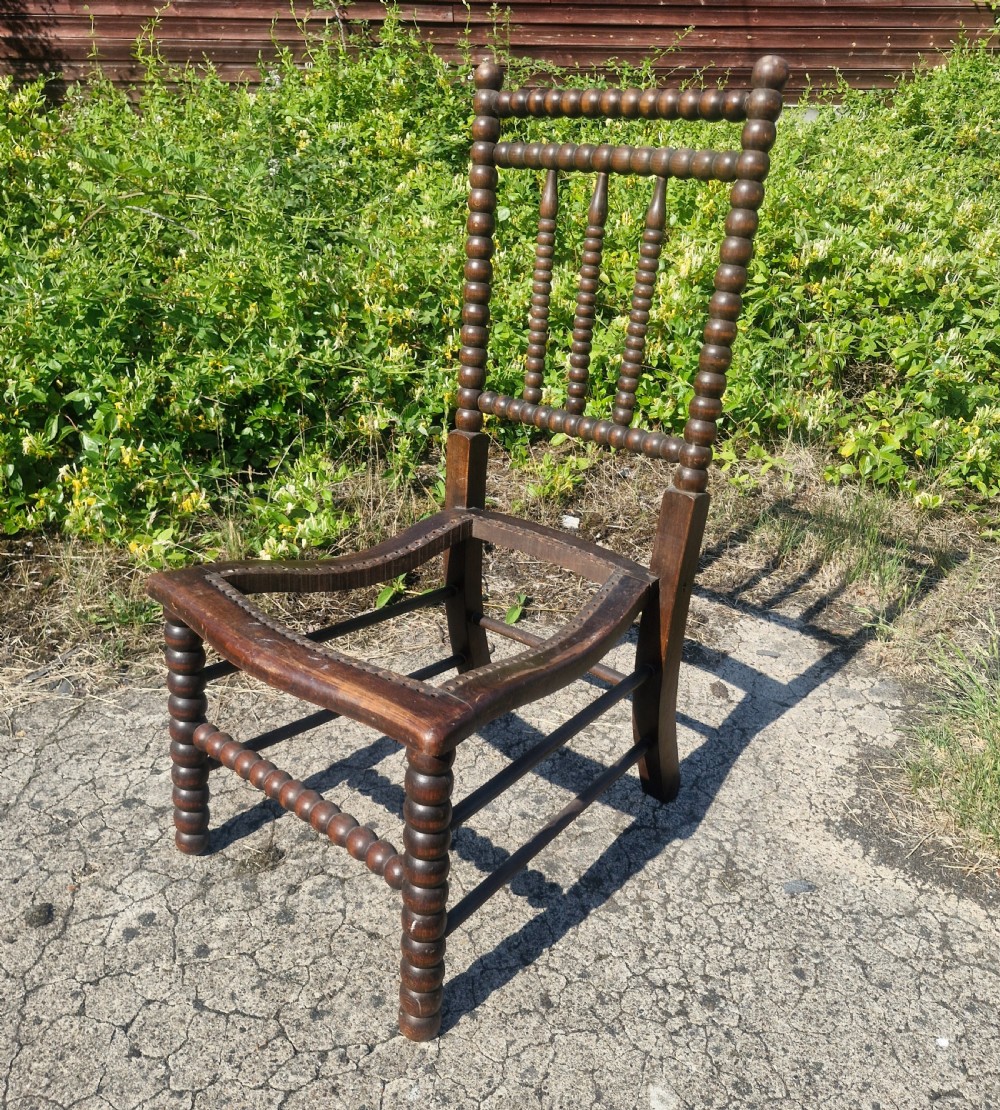 A dark brown wooden bedroom chair featuring bobbin-turned uprights and an open seat frame. View II