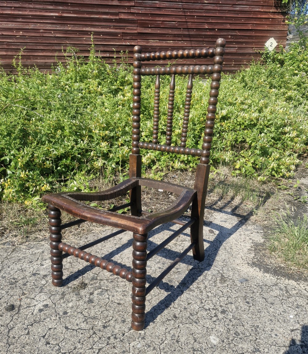 A dark brown wooden bedroom chair featuring bobbin-turned uprights and an open seat frame. View III