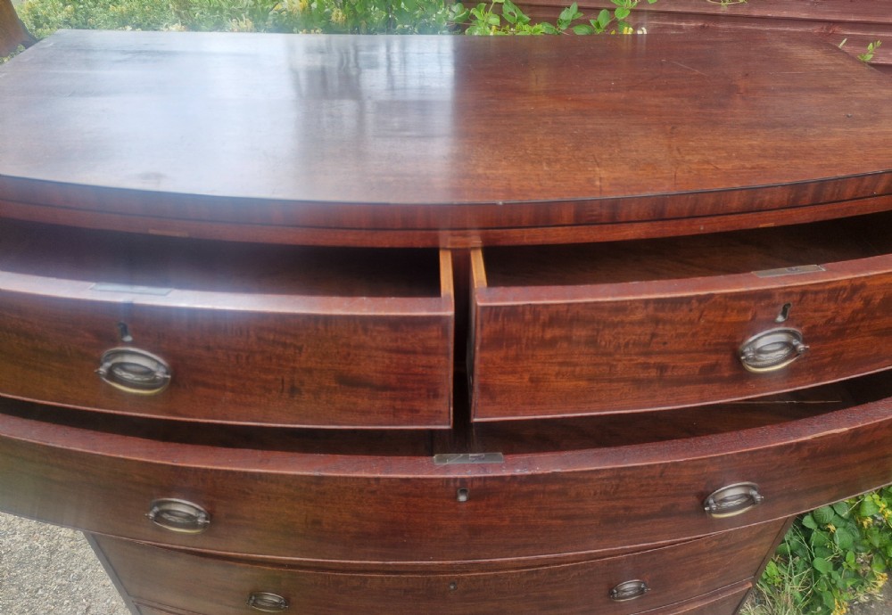 A Regency mahogany bow front chest of drawers featuring two short over three long graduated drawers with brass handles and splayed bracket feet. View IV