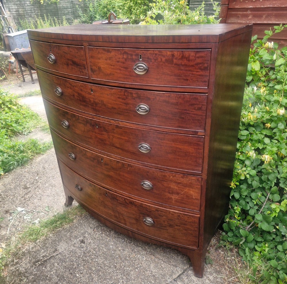 A Regency mahogany bow front chest of drawers featuring two short over three long graduated drawers with brass handles and splayed bracket feet. View V