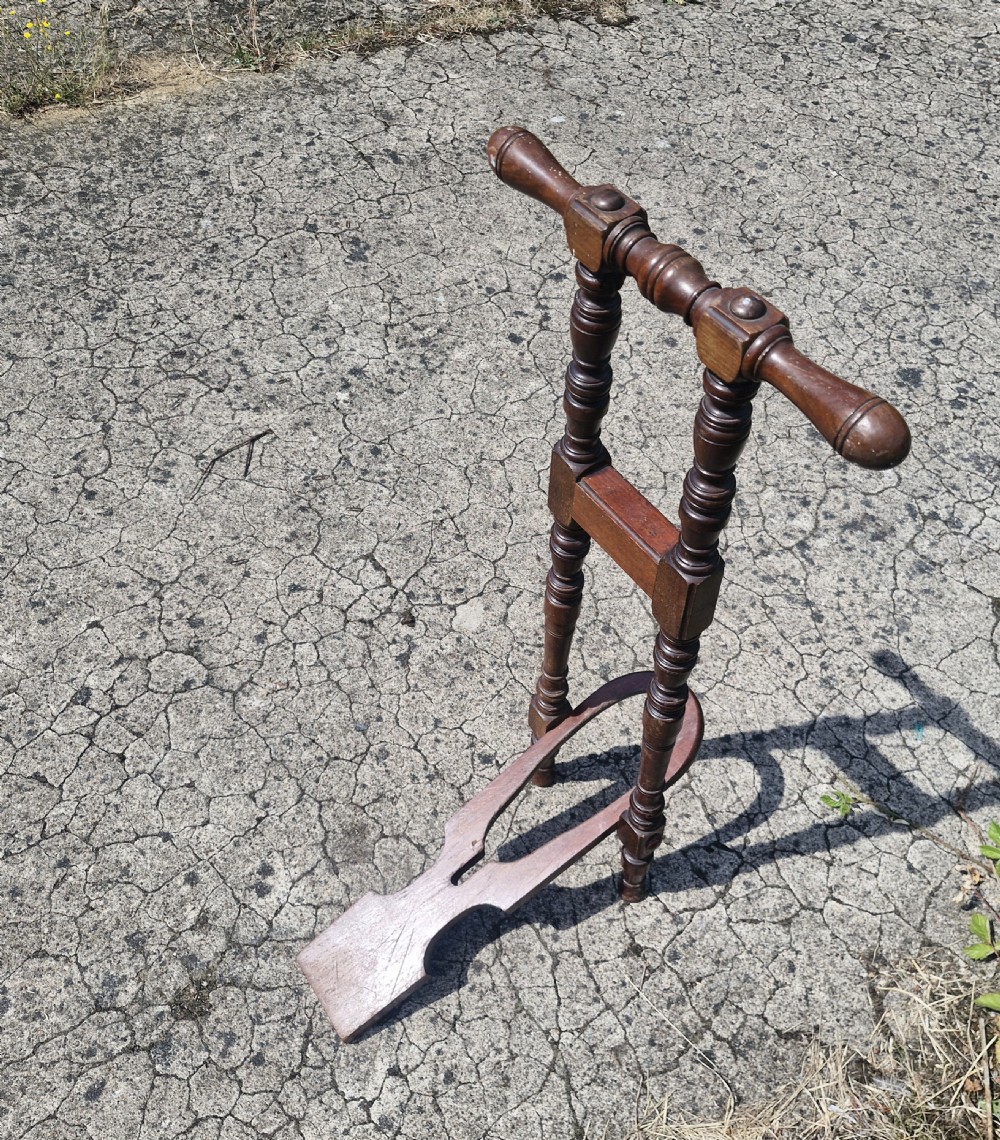 A late Victorian turned dark wood freestanding boot jack with twin upright handles and a horseshoe-shaped base for boot removal. View II