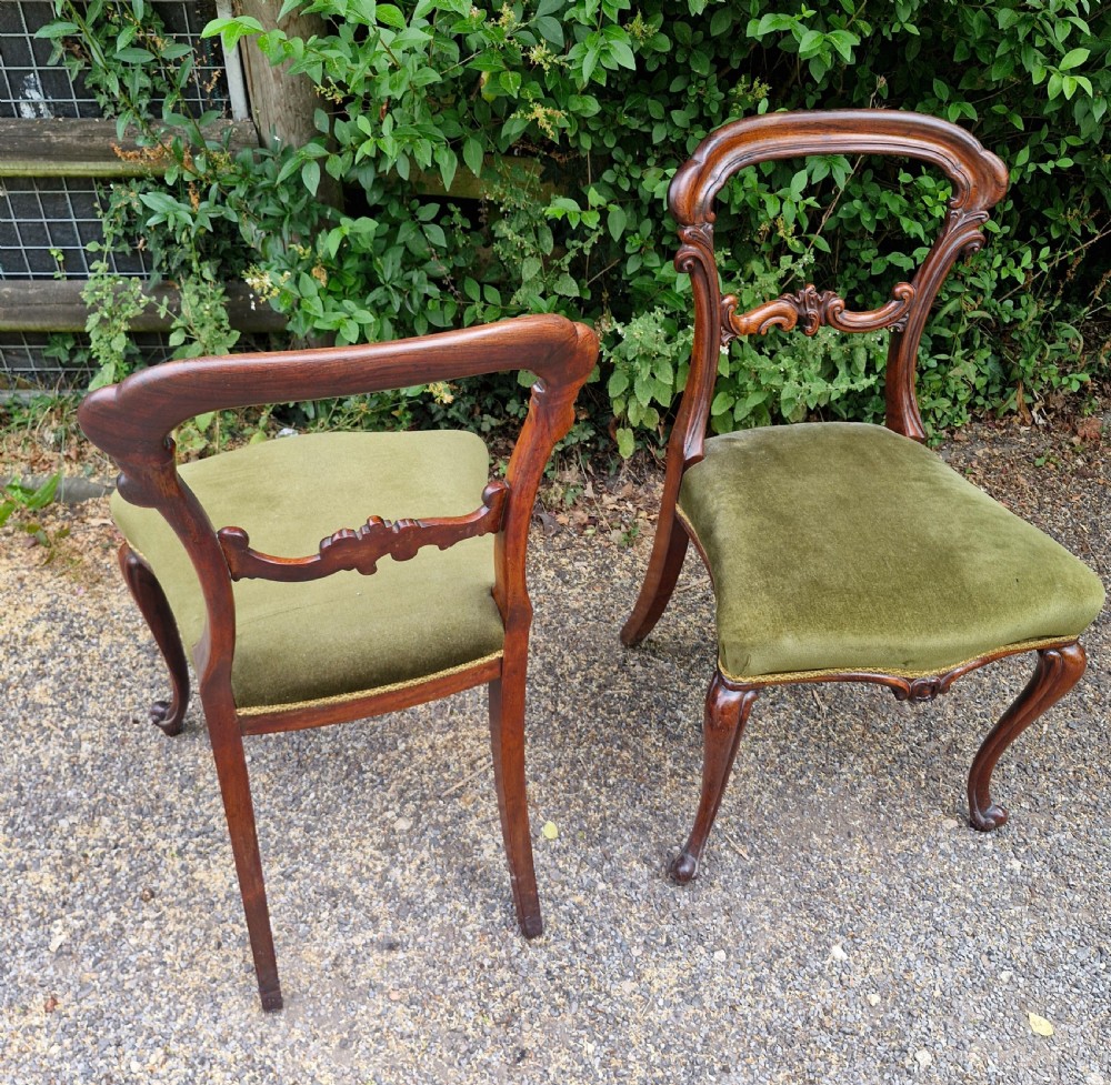 A pair of early Victorian rosewood balloon back side chairs featuring carved foliate splats, cabriole front legs, and green velvet upholstered seats. View II