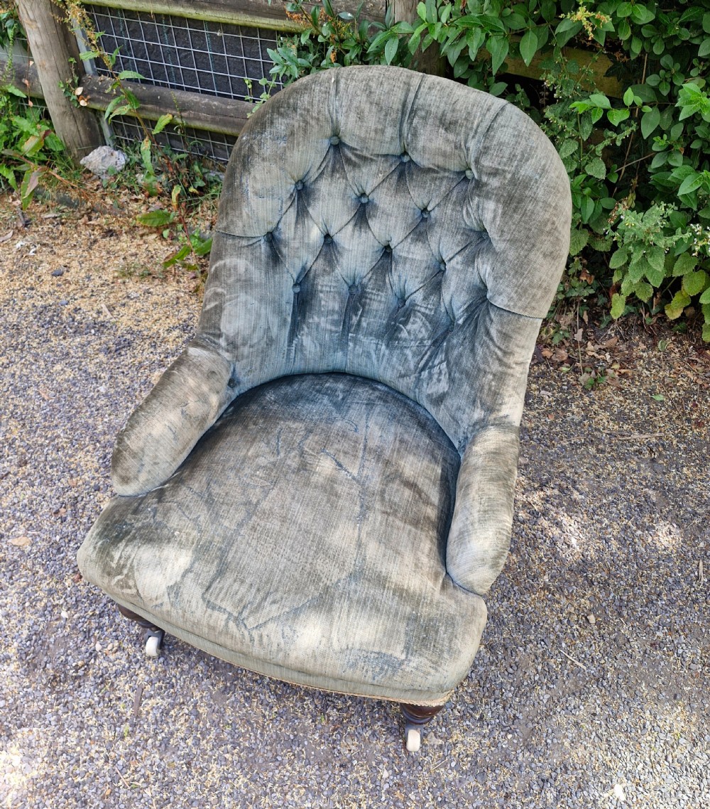A Victorian button-back armchair upholstered in slate blue velvet featuring turned wooden front legs on castors. View II