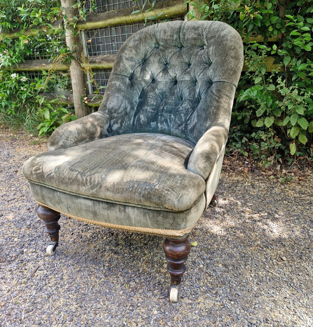 A Victorian button-back armchair upholstered in slate blue velvet featuring turned wooden front legs on castors. View III