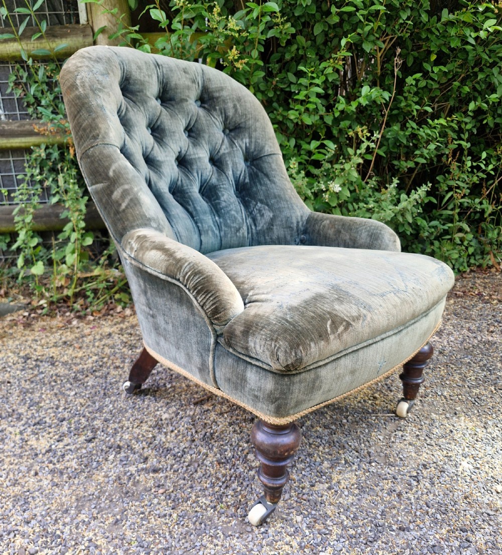 A Victorian button-back armchair upholstered in slate blue velvet featuring turned wooden front legs on castors. View IV