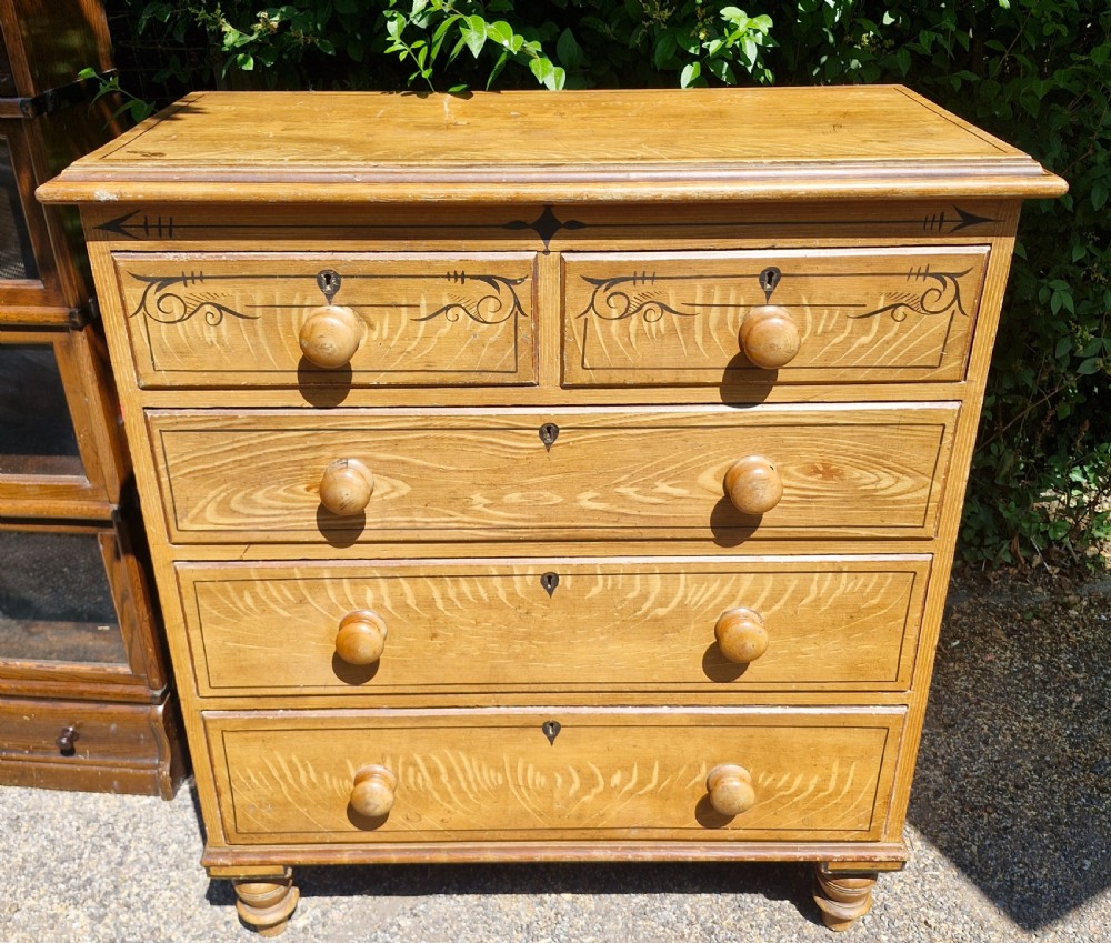 A Victorian scumbled pine chest of drawers featuring two short drawers over three long drawers with turned wooden handles and hand-painted decorative border detailing.