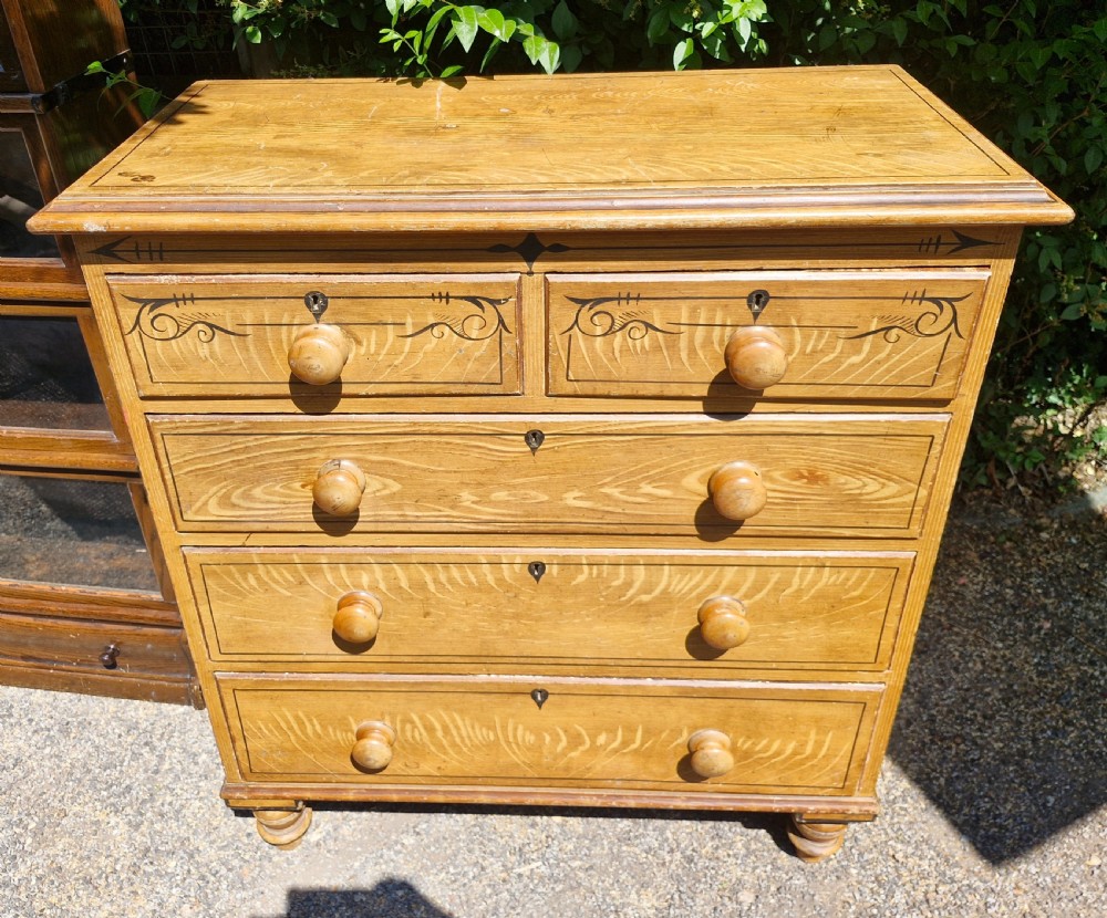 A Victorian scumbled pine chest of drawers featuring two short drawers over three long drawers with turned wooden handles and hand-painted decorative border detailing. View II