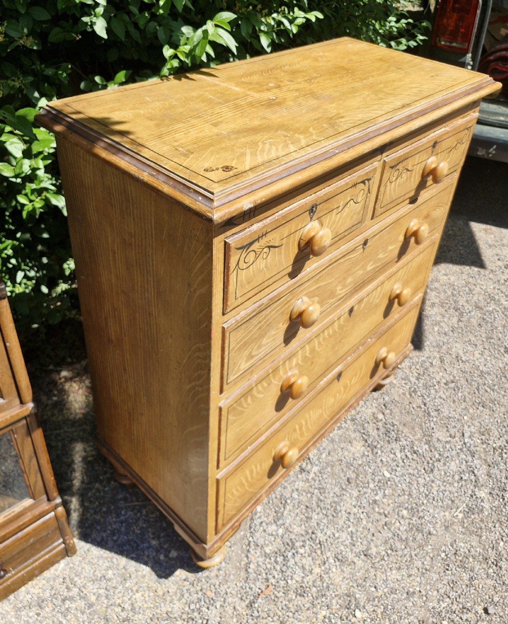 A Victorian scumbled pine chest of drawers featuring two short drawers over three long drawers with turned wooden handles and hand-painted decorative border detailing. View III