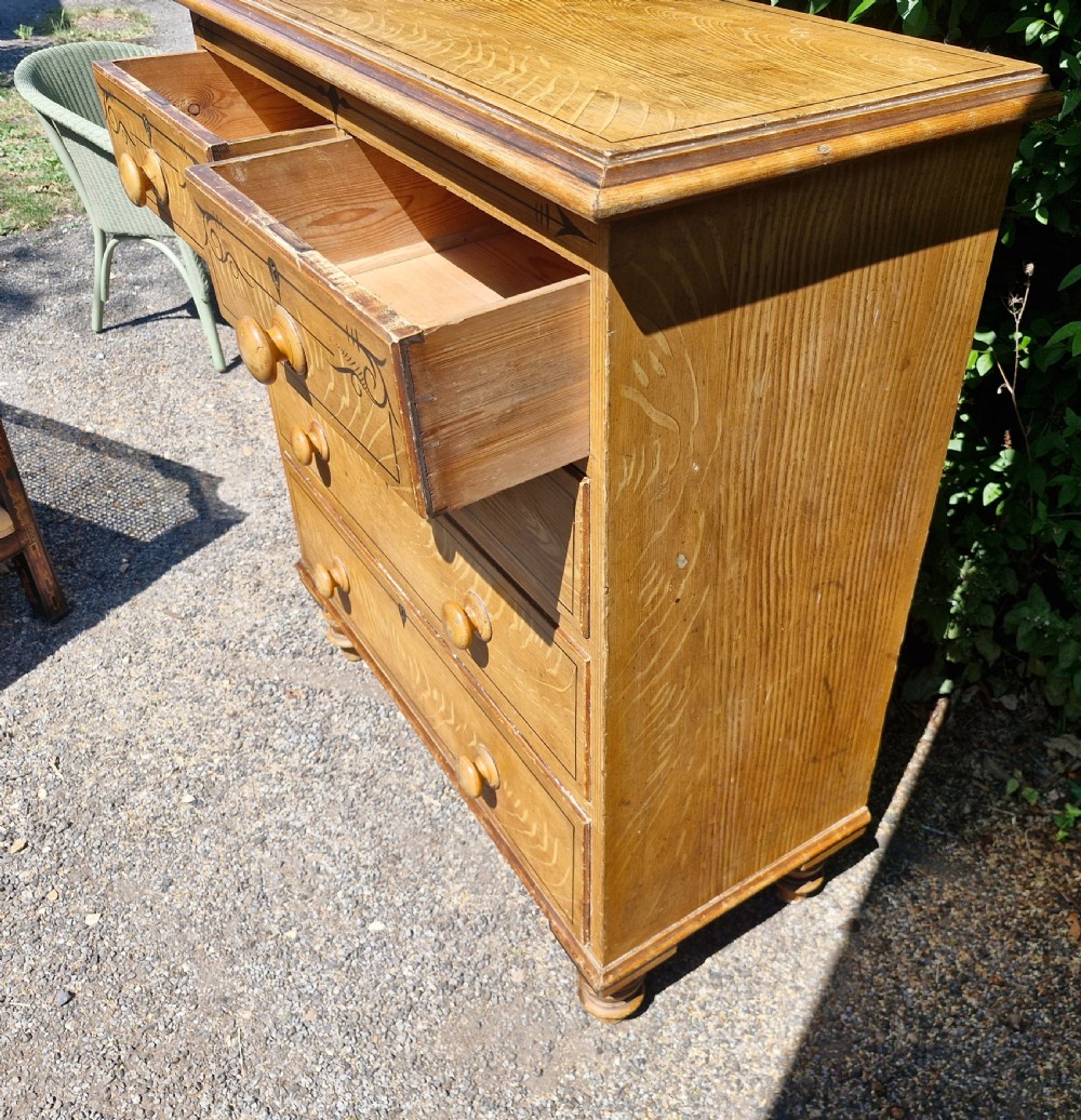 A Victorian scumbled pine chest of drawers featuring two short drawers over three long drawers with turned wooden handles and hand-painted decorative border detailing. View IV