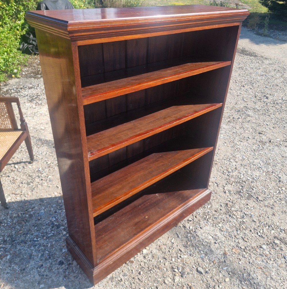 A low dark mahogany open front bookcase featuring four shelves, a moulded top, and a solid plinth base. View IV
