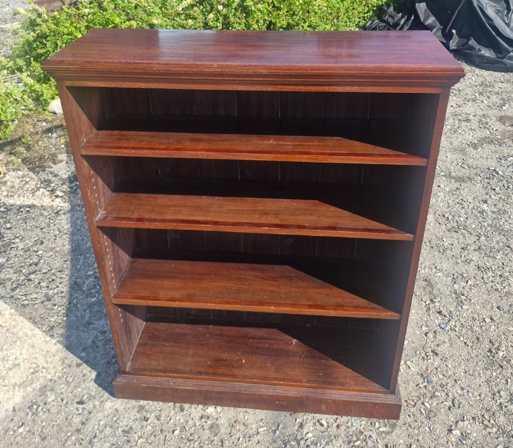 A low dark mahogany open front bookcase featuring four shelves, a moulded top, and a solid plinth base. View VI