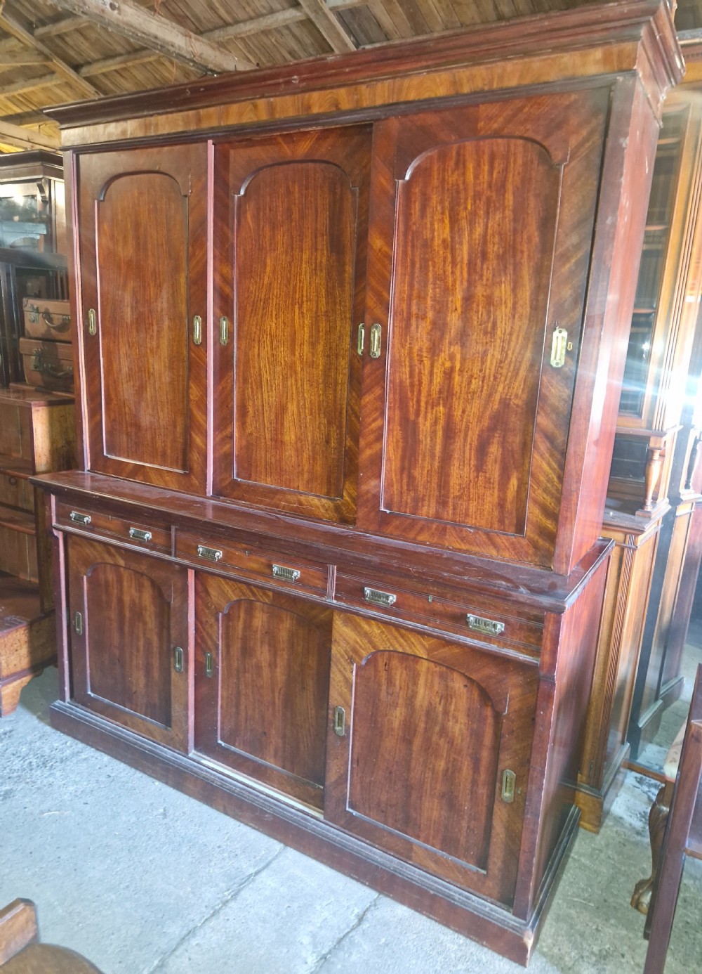 Large Victorian mahogany estate office cabinet with arched panelled sliding doors and lower drawers.
