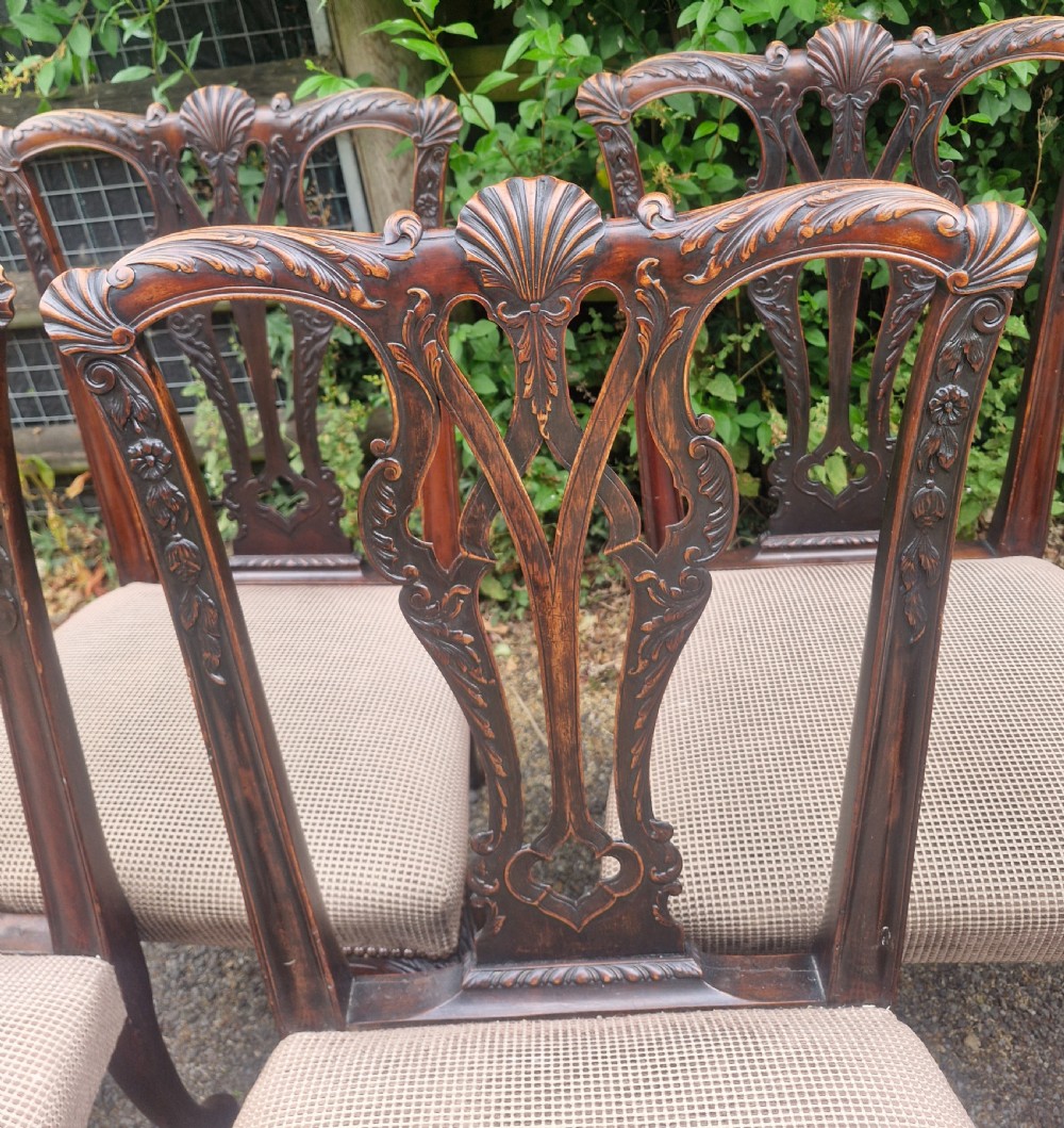 A set of eight dark mahogany Chippendale style dining chairs featuring carved splat backs, cabriole legs with ball and claw feet, and neutral patterned fabric seats. View X