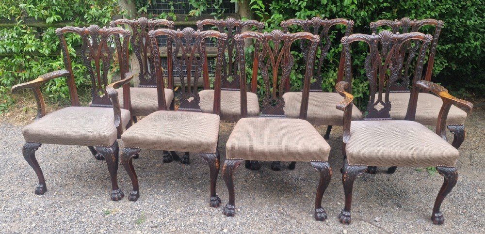 A set of eight dark mahogany Chippendale style dining chairs featuring carved splat backs, cabriole legs with ball and claw feet, and neutral patterned fabric seats. View XI
