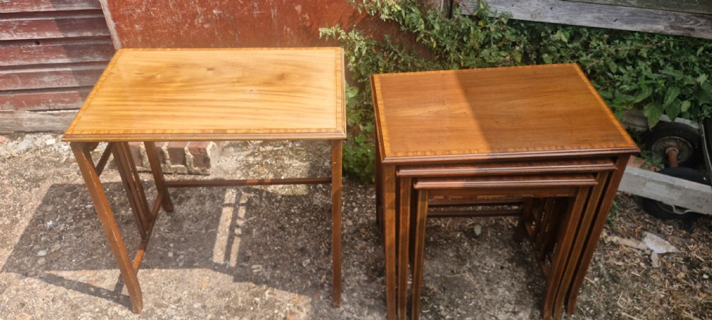 A set of three graduated Edwardian mahogany nesting tables featuring satinwood line inlay on the tops and slatted side supports. View II