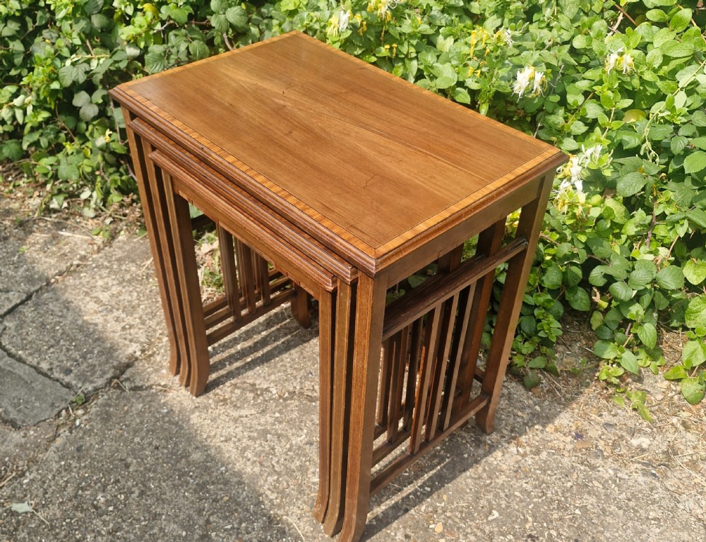 A set of three graduated Edwardian mahogany nesting tables featuring satinwood line inlay on the tops and slatted side supports. View IV