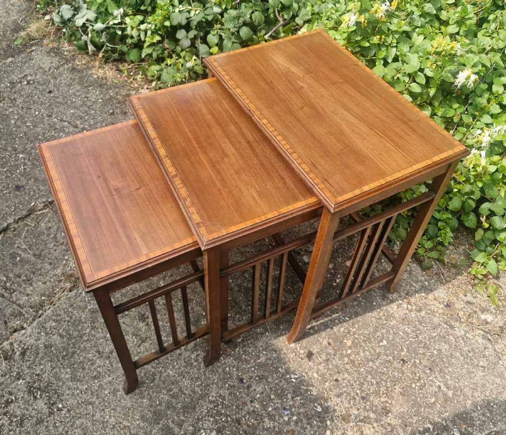 A set of three graduated Edwardian mahogany nesting tables featuring satinwood line inlay on the tops and slatted side supports. View V