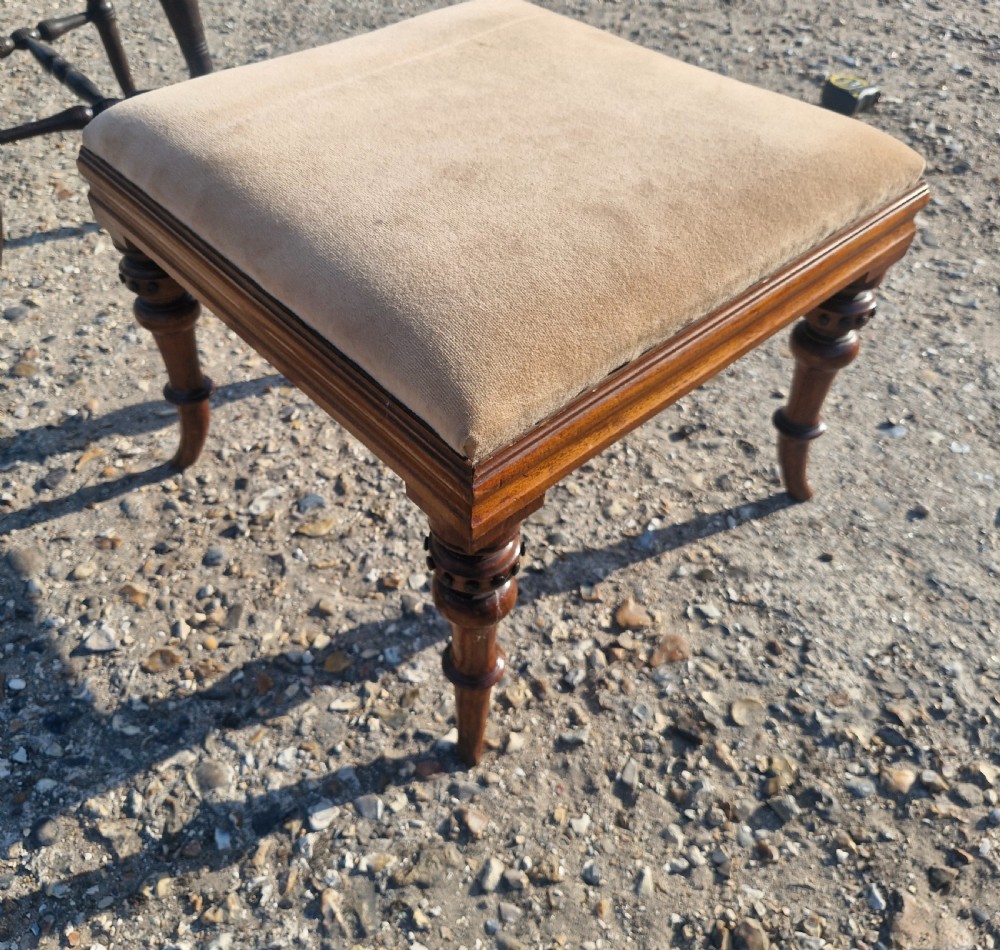 A square Victorian footstool featuring turned wooden legs and a beige upholstered padded top. View III