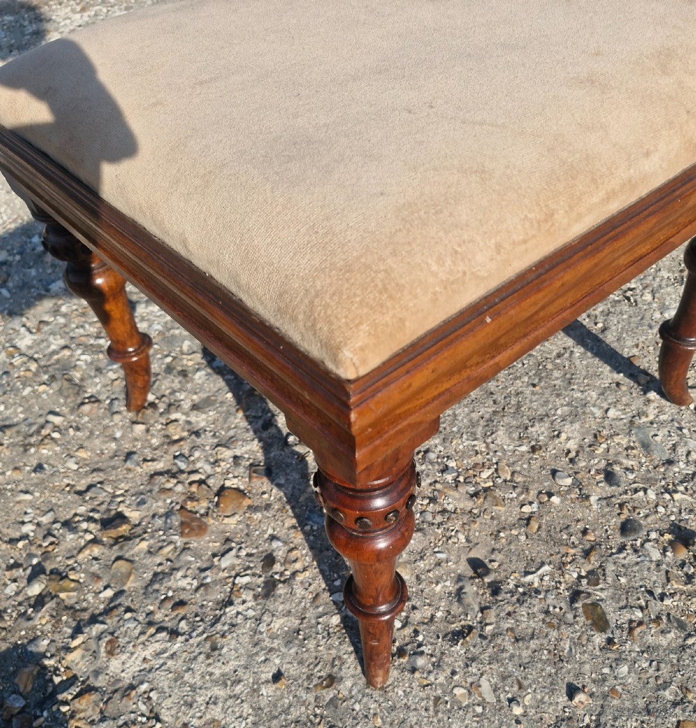 A square Victorian footstool featuring turned wooden legs and a beige upholstered padded top. View IV