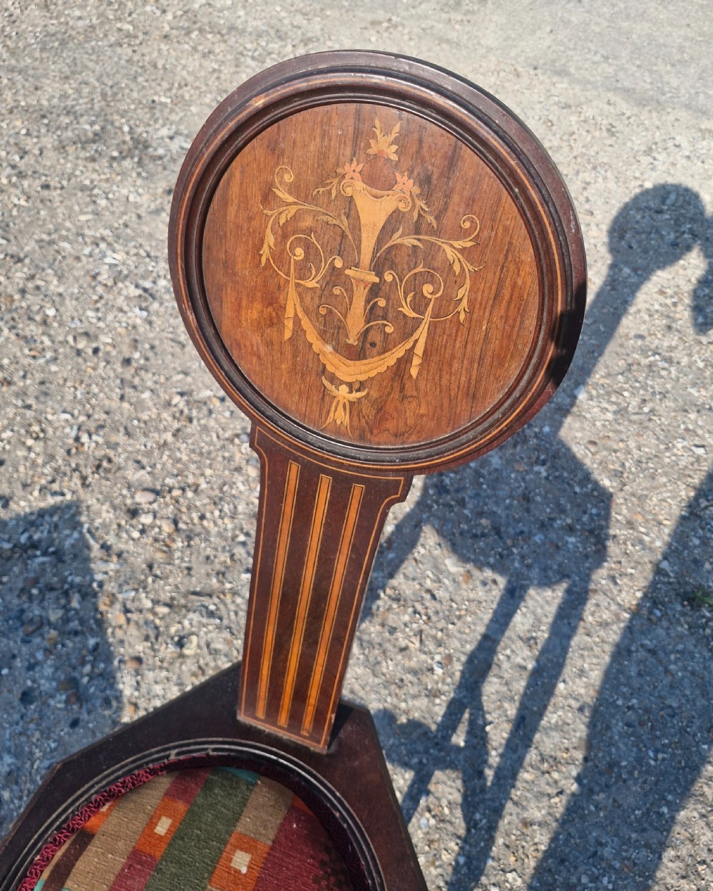 An Edwardian dark wood spinning chair featuring a tall narrow backrest with marquetry inlay and an upholstered circular seat within a hexagonal frame. View V