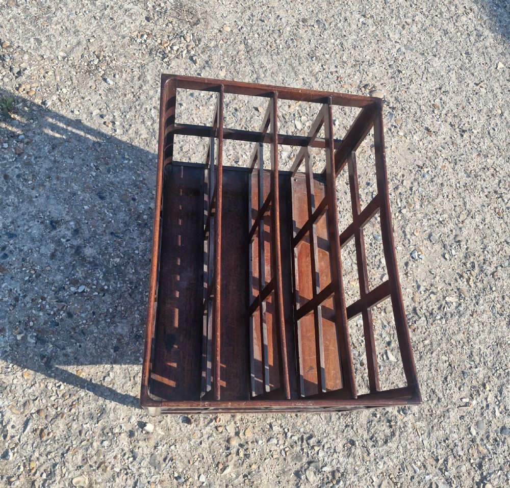 A 19th century mahogany Canterbury with slatted vertical divisions, a lower base drawer with brass knobs, and turned legs with brass castors. View II
