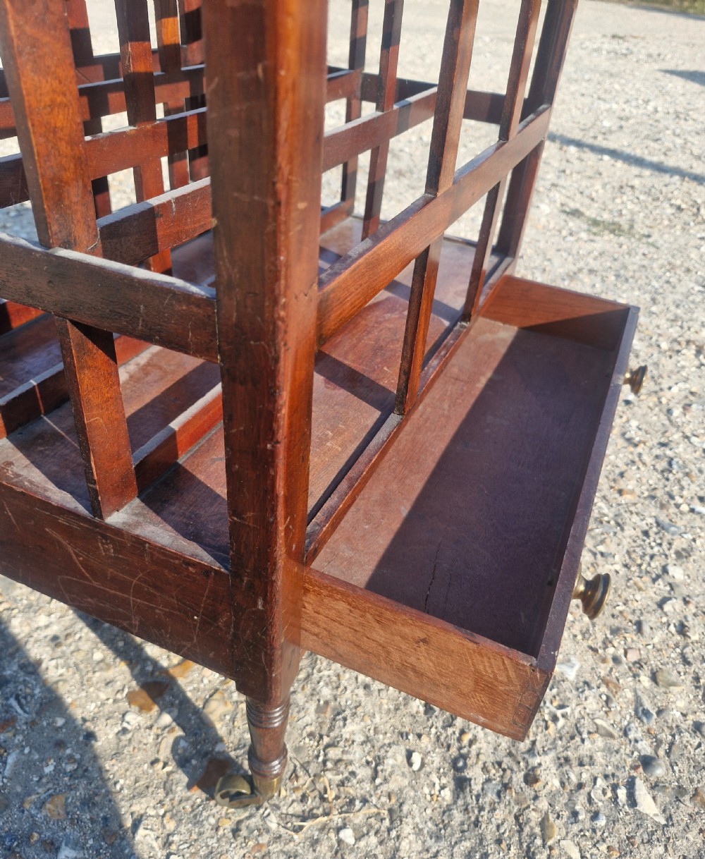 A 19th century mahogany Canterbury with slatted vertical divisions, a lower base drawer with brass knobs, and turned legs with brass castors. View III