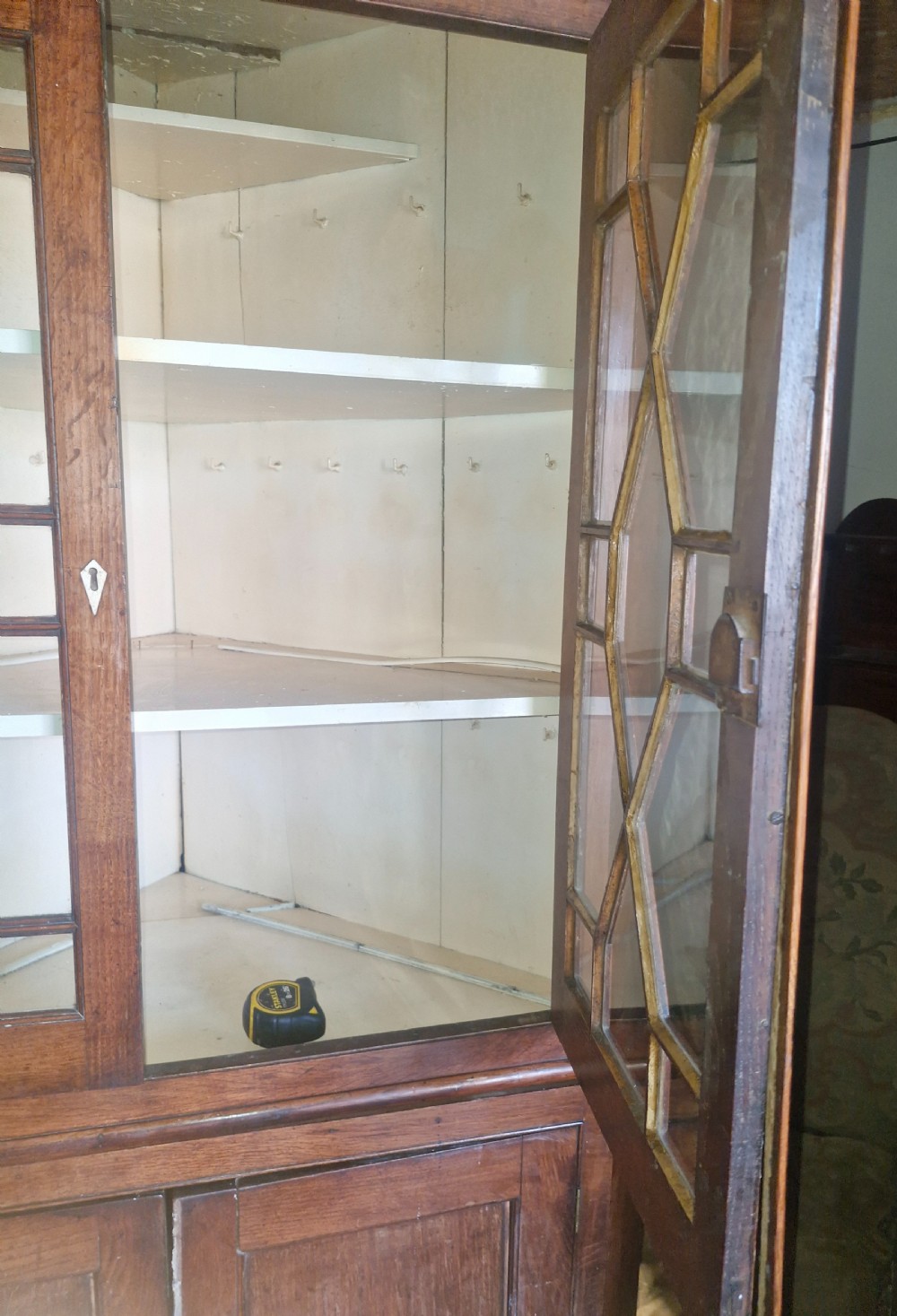An antique two-part Welsh oak corner cupboard featuring upper astragal glazed doors with geometric panes and lower panelled cupboard doors. View II