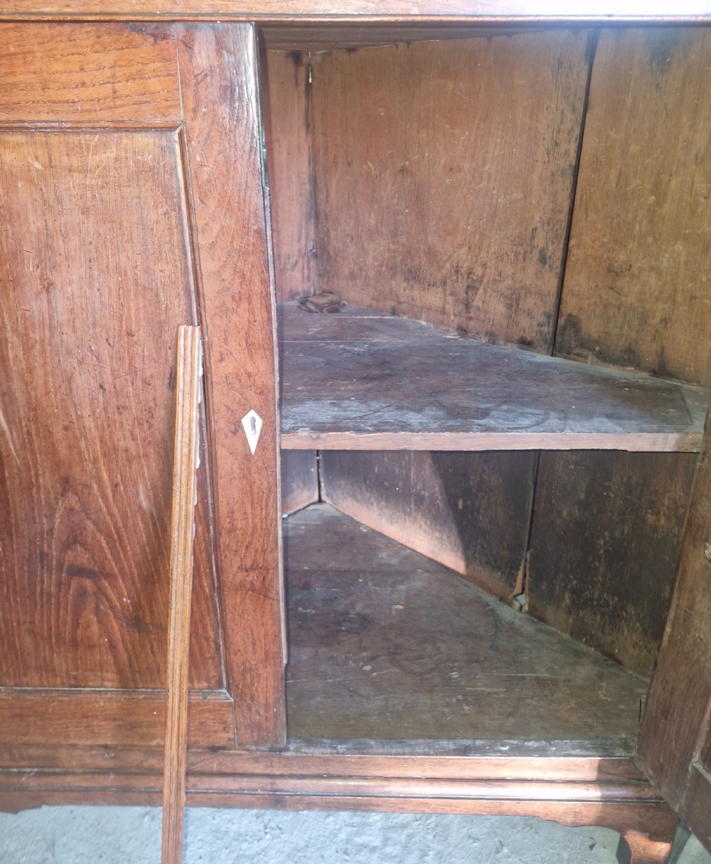 An antique two-part Welsh oak corner cupboard featuring upper astragal glazed doors with geometric panes and lower panelled cupboard doors. View VII