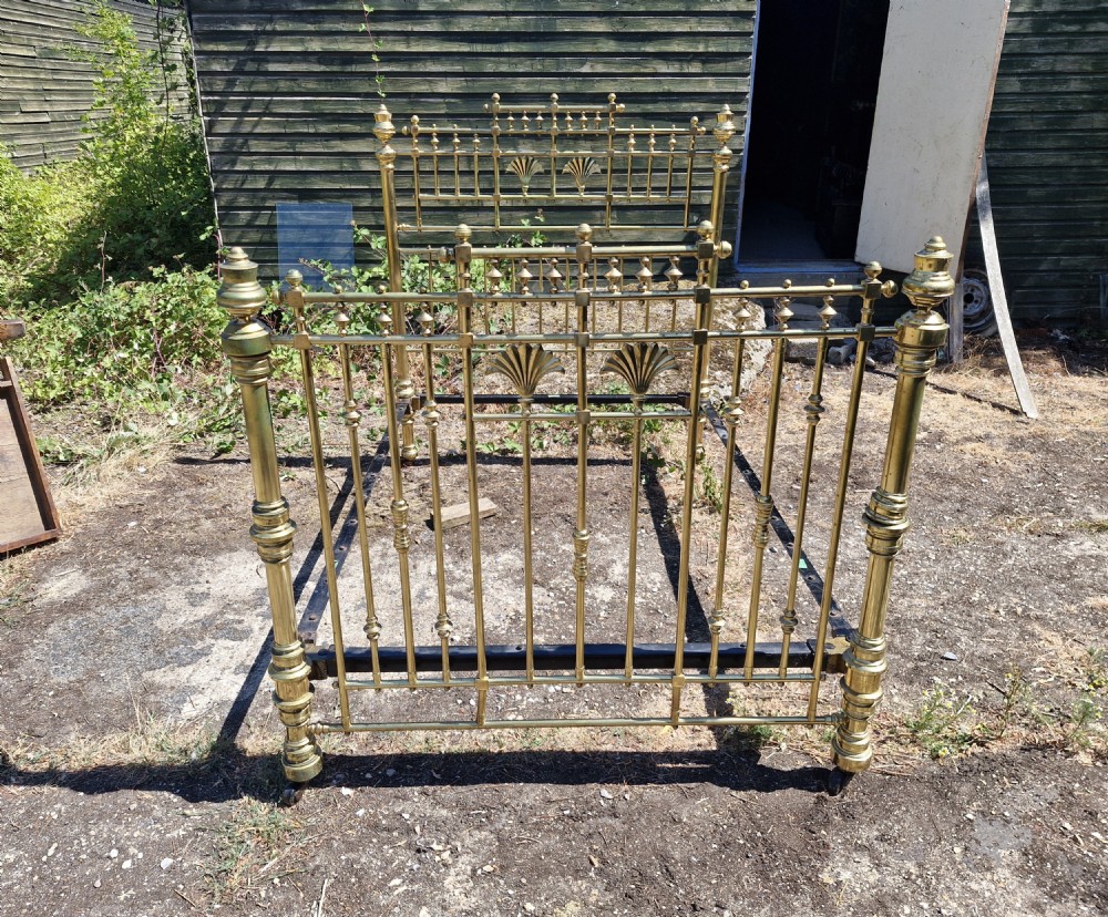 A Victorian double brass bed frame featuring turned posts, decorative finials, vertical metal spindles, and cast iron side rails. View V