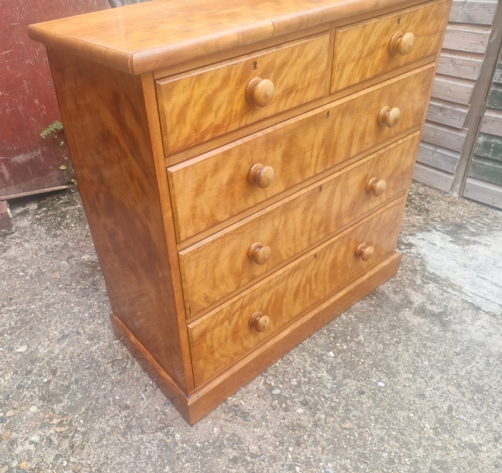 A Victorian satin birch chest of drawers featuring two short drawers over three long graduated drawers with turned wooden handles. View VI