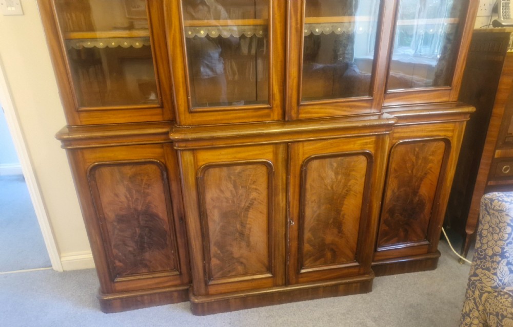 A large Victorian mahogany breakfront library bookcase featuring four glazed upper doors and panelled lower cupboard doors on a plinth base. View V