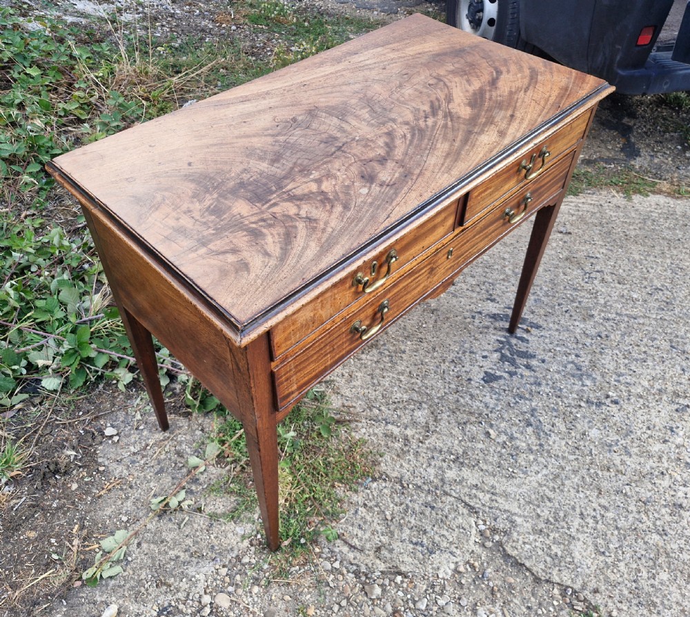 An early 19th-century mahogany side table featuring a rectangular top, three drawers with brass handles, and slender square tapered legs. View II