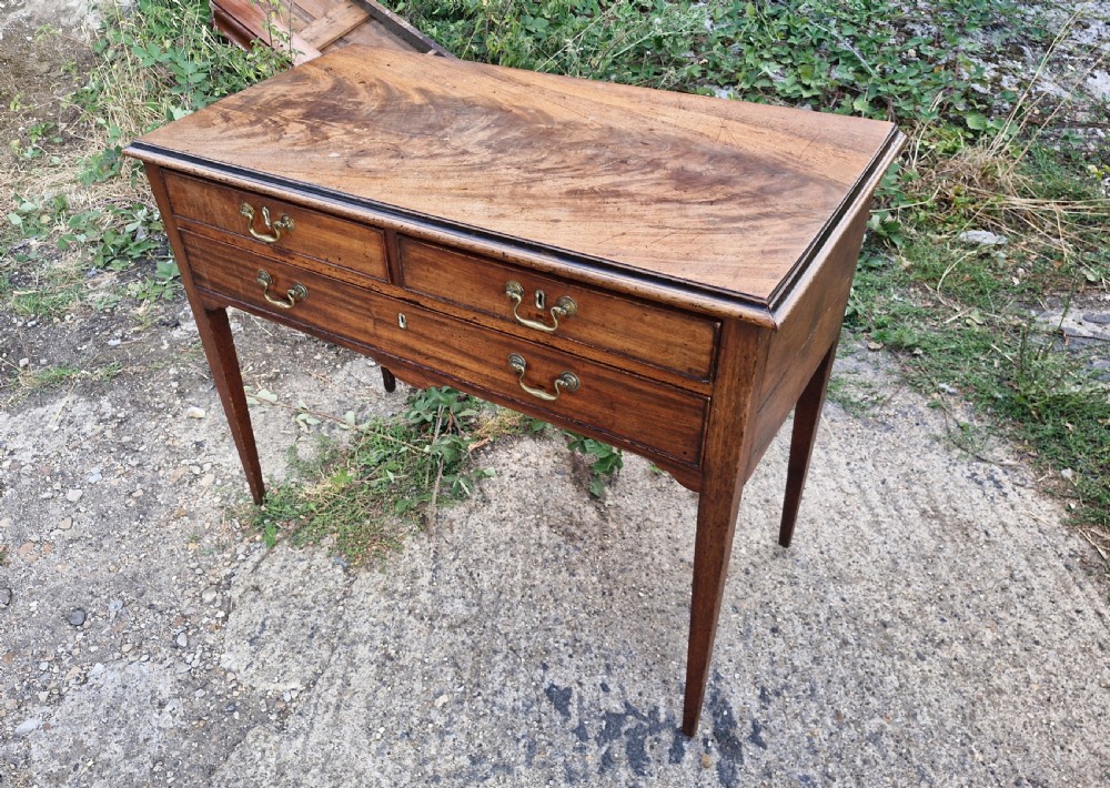 An early 19th-century mahogany side table featuring a rectangular top, three drawers with brass handles, and slender square tapered legs. View III