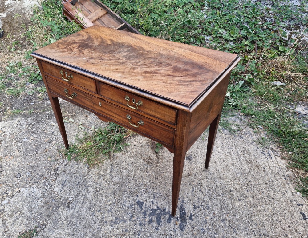 An early 19th-century mahogany side table featuring a rectangular top, three drawers with brass handles, and slender square tapered legs. View V
